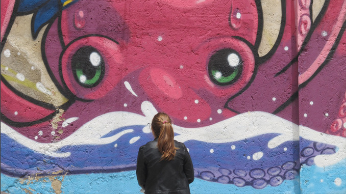 Una ragazza osserva il murale "U purpu"